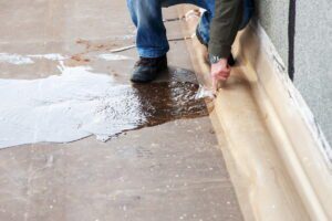 Technician inspecting water pooling and slab damage to locate a leak.