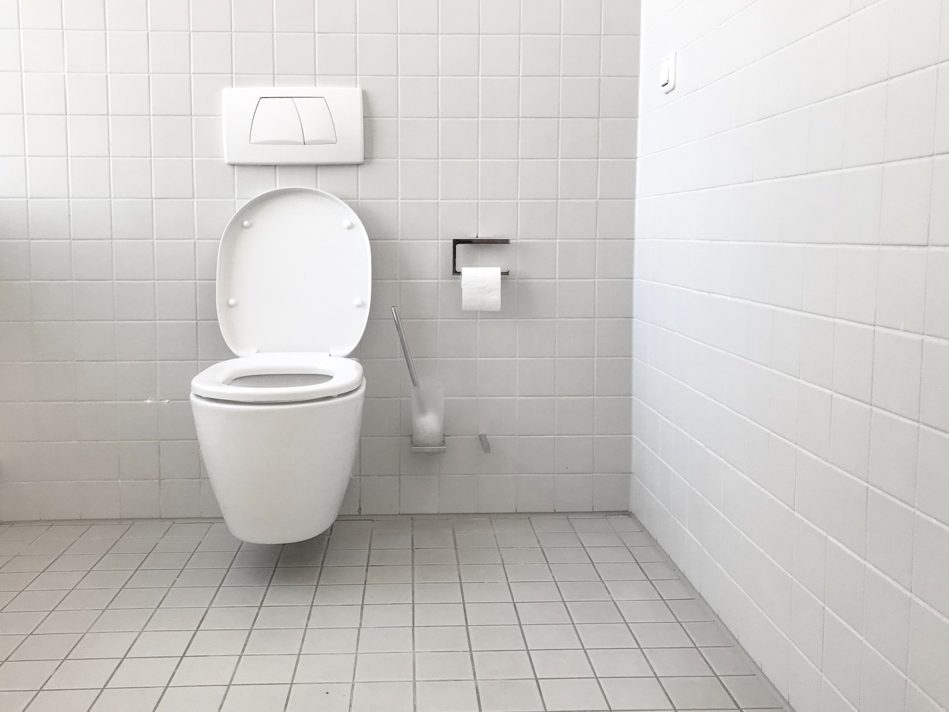 White modern toilet against tiled wall in a bathroom.