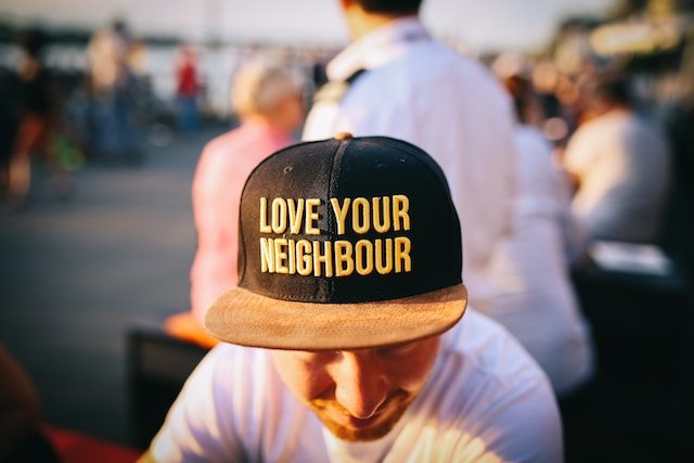 Person wearing a cap with the message “Love Your Neighbour”