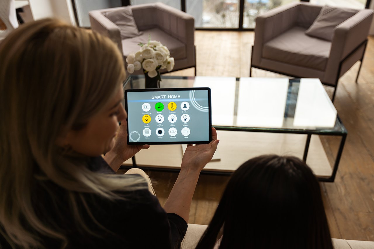 Person holding a tablet displaying a smart home control interface.