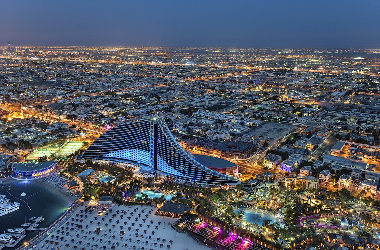 Aerial night view of the Jumeirah Beach Hotel and surrounding Dubai coastline.