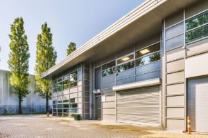 Modern commercial industrial building exterior with metal panel walls and large windows.