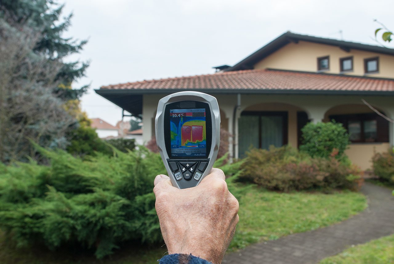 Thermal imaging device scanning a residential home to identify hidden heat and moisture anomalies.