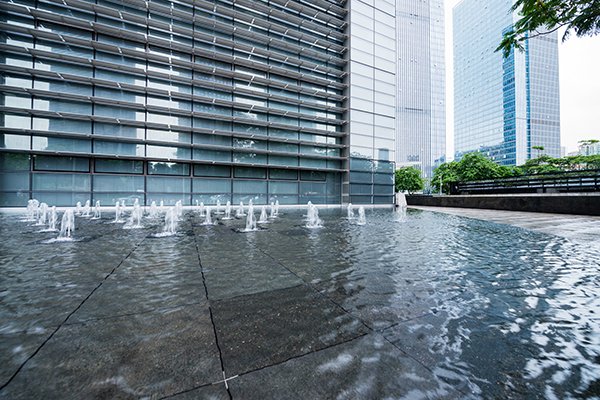 Office building with a water fountain in front, highlighting commercial water systems for leak detection in Dubai.