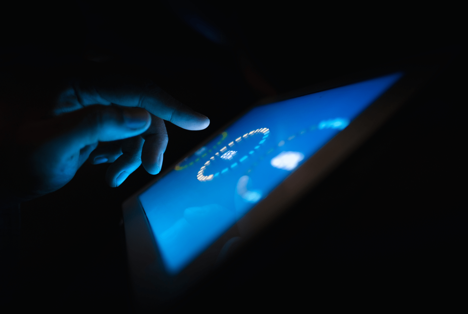 Hand using touchscreen with glowing blue interface representing IoT digital leak monitoring